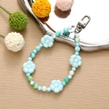 Detailed close-up of handmade blue acrylic flower charms on a beaded phone strap - Blue