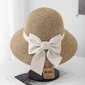 Close-up of woven straw sun hat with elegant beige ribbon bow and UV protection tag - Adjustable / Beige Bow Natural Straw Hat