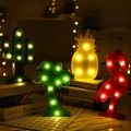Scena accogliente con luci LED a cactus, fenicottero e ananas sui libri - Albero di Natale
