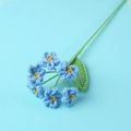 Macro view of hand-knitted blue forget-me-not crochet flowers with yellow stamens and green leaf - Finished 6-head Forget-me-not Bouquet (blue)