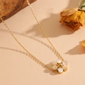 Detail of a gold floral necklace with white cat-eye stone petals on a beige natural background - Gold White Cat's Eye Necklace
