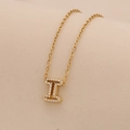 Close-up of golden letter I pendant with sparkling pavé crystals on a delicate chain - Letter I