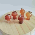 Mini mushroom natural stone pendants in orange-brown tones on a wooden stand - Red Agate