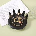 Unique black hand shaped resin jewelry tray for rings and necklaces on a green desk - Black Hand Shape