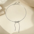 Close-up of silver bow pendant on flat snake bone chain with adjustable lobster clasp - 14k / Silver Necklace