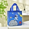 Detail of blue non-woven astronaut gift bag with space patterns on a white table - Astronaut Style 3 / 23x22x11cm