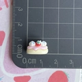 Close-up of a tiny strawberry cake resin charm showing 1.5cm size on a scale - Cream Strawberry Sponge Cake