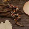 Macro shot of retro rhinestone snake brooch on a vintage wood and maple leaf background - Coffee Full Rhinestone Snake
