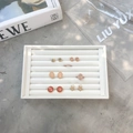 Velvet jewelry display tray featuring assorted gold-plated earrings and minimalist rings - Small White PU Leather Slot Tray - No Lid