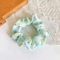 Detailed view of light green fabric scrunchie with lemon patterns on lace background - Green Cherry Large