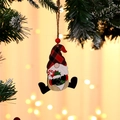 Close-up of wooden Christmas gnome ornament with red plaid hat and candy cane detail - Green Sock Style