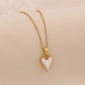 Collier en chaîne dorée avec pendentif cœur émaillé blanc sur fond clair texturé - Blanc