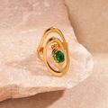 Macro shot of a gold spiral ring with an oval green zircon gemstone on a stone - Green Artistic Spiral