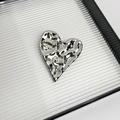 Close-up of heart-shaped silver brooch with irregular metallic texture on a tray - 32 Silver Heart (Z-2507)