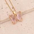 Detailed view of pink butterfly pendant with gold chain and zircon accents on stone - Pink