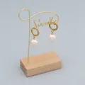 Dettaglio di orecchini eleganti con perle e sfere dorate su un supporto Smile di classe - Bianco