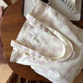 Detailed close-up of a cream cotton tote bag with a purple polka-dot bow on a wooden table - Light Purple Polka Dot Bow