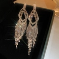 Close-up of luxury long tassel earrings with sparkling crystals in a black velvet box - Gold
