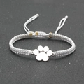 Close-up of handmade white braided lucky bracelet with silver dog paw print charm - White