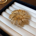Macro detail of a vintage golden floral brooch presented in a soft velvet jewelry gift box - Gold Radial Flower