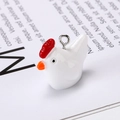 Macro shot of a cute white resin chicken pendant with a red comb and metal ring detail - Chicken