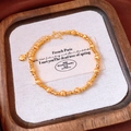 Vista macro del bracciale di perline placcato oro 24k con ciondolo a cuore su legno - Stile Perline Rotonde Sfaccettate Opache