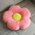 Pink flower-shaped plush seat cushion with yellow center on a grey striped sofa - Watermelon red