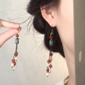 Detailed macro shot of vintage Chinese style long tassel earrings with pearls on model - Hook Style / Gold-Red-Blue