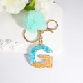 Letter G keychain with blue shell resin, gold glitter, and turquoise pom pom charm - Letter G