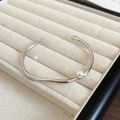 Primer plano detallado de un brazalete plateado ondulado con una sola perla blanca redonda - Estilo de Plata con Perla