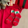 Plush red Christmas socks with green tree pattern in a cozy holiday gift setting - Red Christmas Tree