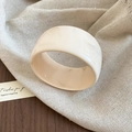 Detail van crème acrylhars armband met marmertextuur op een vintage houten tafel - Beige (Wolkpatroon)