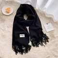 Classic black fringed scarf with detailed fabric composition label on soft plush carpet - Black