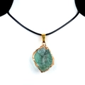 Green raw gemstone pendant with gold-plated trim and black cord necklace on a model - Fluorite