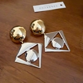 Macro detail van tweekleurige geometrische oorbellen met gouden knopjes en zilveren kaders - Zilveren Pin - Goud - Zilver