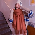 Caramel wool cashmere scarf with tassels shown with a knit hat in a cozy indoor setting - Brick Red