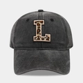 Detail of washed black baseball cap featuring a leopard print embroidered letter L patch - Letter L