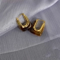 Chic U-shaped gold metal earrings with amber resin detail on soft silk background - Amber