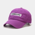 Detail showing the white rectangular patch with Founded 1986 embroidery on a purple cap - Adjustable / Purple
