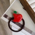 Close-up of red apple hair tie with green leaf detail and brown elastic band - Apple