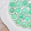 Macro detail of iridescent light green round beads with core holes on a ceramic plate - Green