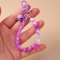 Detail of purple star beaded keychain featuring a metal bell and secure lobster clasp - Purple