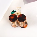 Macro shot of tortoiseshell hair claw with green gemstone detail on magazine background - Tortoiseshell Cherry