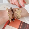 Dettaglio di un set di gioielli con fiori in metallo dorato e bracciali tartarugati - Set di 3 pezzi / Oro & Marrone