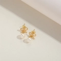 Close-up detail of golden bow earrings with pearl pendants on a neutral surface - Bowknot with Pearl