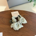 Dettaglio dell'elastico per capelli verde menta con fiocco e perla su legno rustico - Elastico per Capelli con Fiocco Verde Avocado