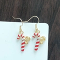 Detail of festive candy cane earrings with golden bows and rhinestones on wood backdrop - Candy Cane with Golden Bow