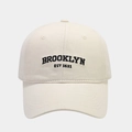 Detailed front view of a cream cotton baseball cap with black Brooklyn embroidery - Adjustable / White