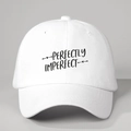 Primer plano del bordado negro 'PERFECTLY IMPERFECT' en una gorra de béisbol blanca vintage - Ajustable / Blanco