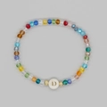 Dettaglio del braccialetto di perline arcobaleno con lettera D dorata su disco bianco - Lettera D